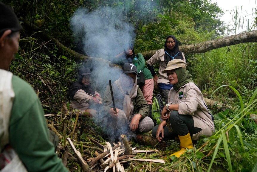 Rangers start a fire as they take a break during a forest patrol.
