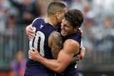 Fremantle Dockers players Michael Walters and Lachie Schultz celebrate a goal with a hug.