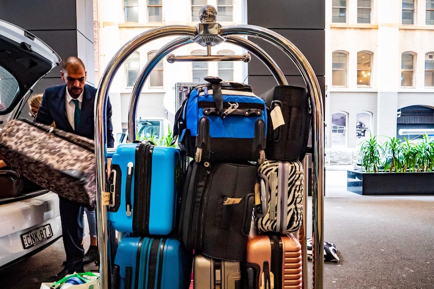 A trolley carries a number of bags, with a man about to load another one on to it.