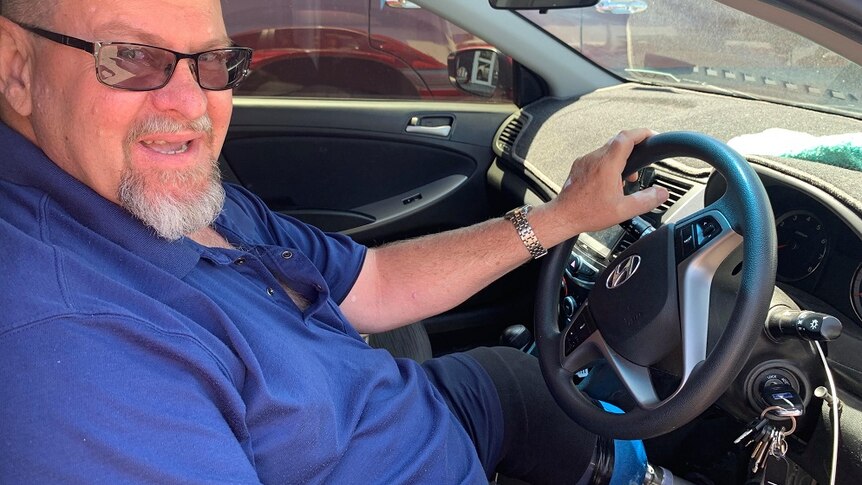 Tom Bundesen sits in his car with a hand on the wheel and his prosthetic leg visible
