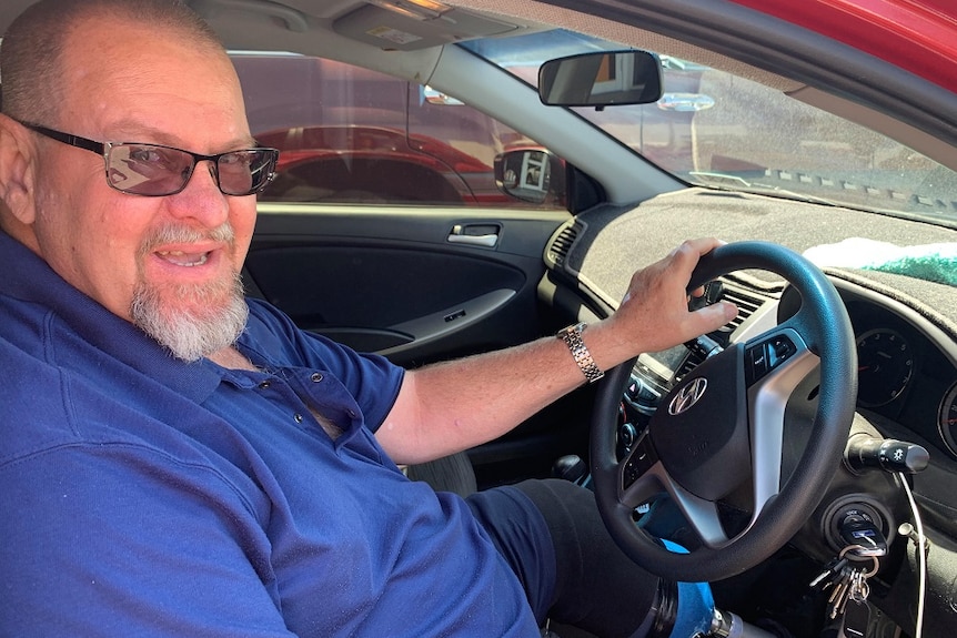 Tom Bundesen sits in his car with a hand on the wheel and his prosthetic leg visible