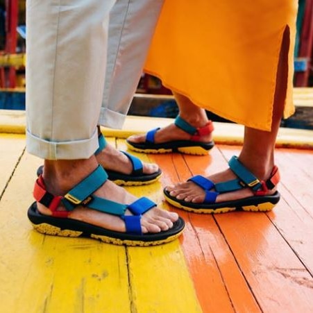 Two pairs of feet wearing matching colourful sandals