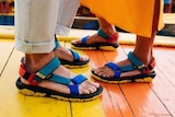 Two pairs of feet wearing matching colourful sandals