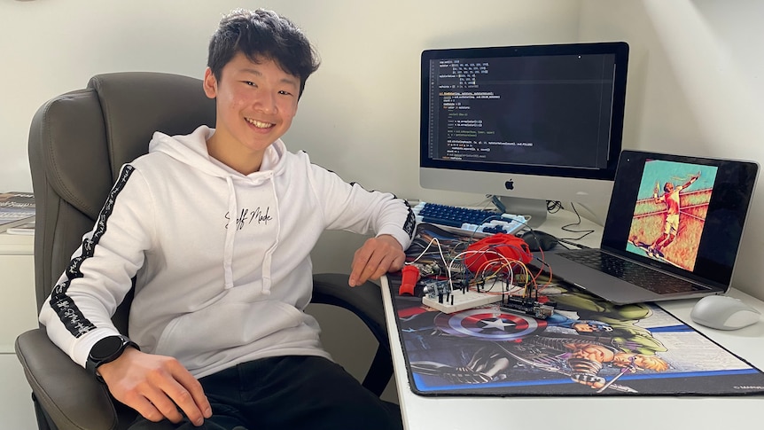 Boy sitting at his desk by his computer, smiling