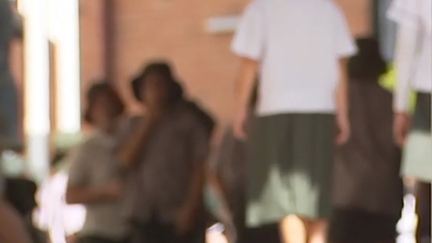 A blurred image of a gathering of high school students in a communal area