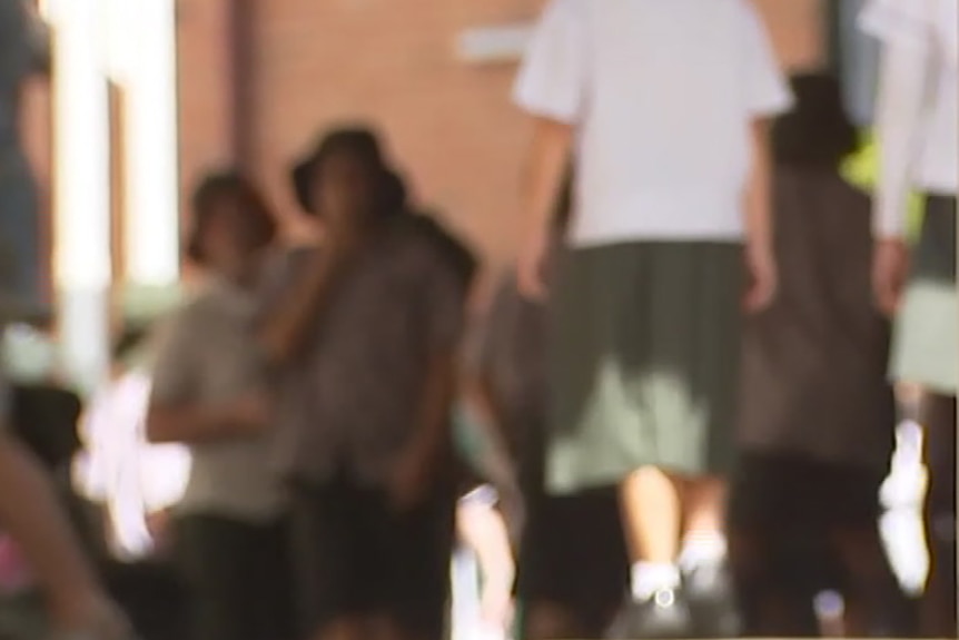 A blurred image of a gathering of high school students in a communal area