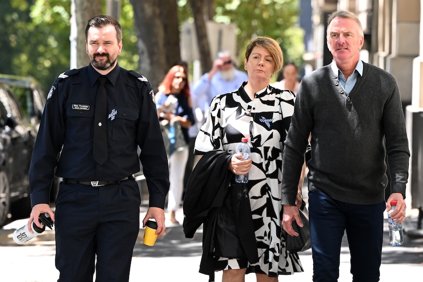 Alex Prestney wearing a police uniform walking next to Belinda and Andrew Prestney outside court.