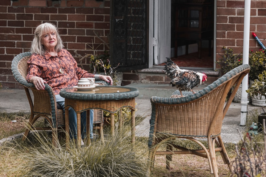 A woman sits on a chair in a backyard.