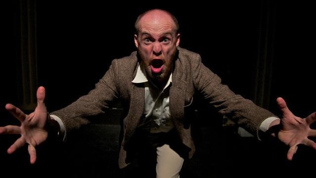 Actor performs with shouting face and hands outstretched
