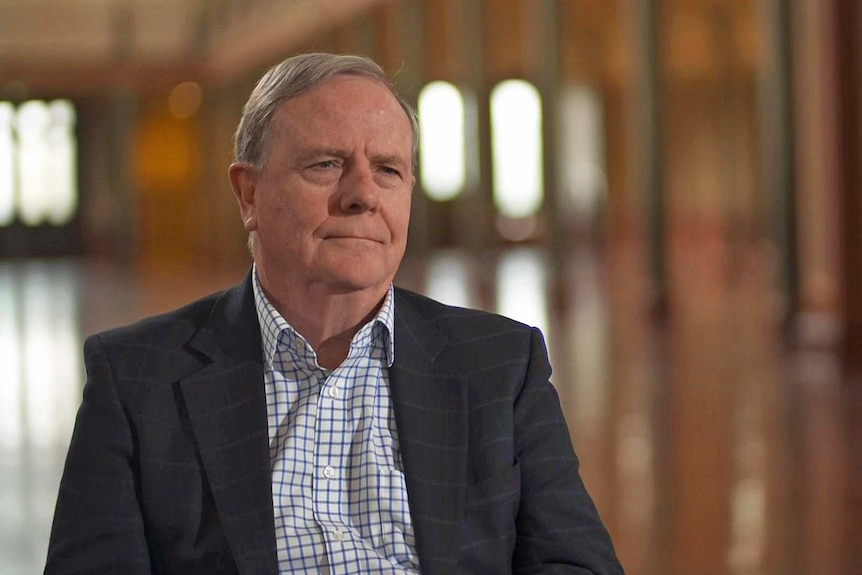 Peter Costello wears a white check shirt and a dark suit jacket.