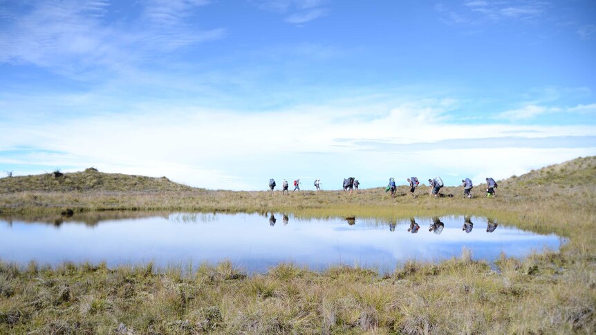 Trekkers pass a lake on Mt Giluwe