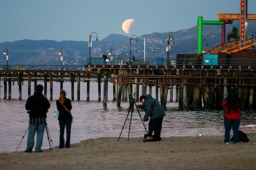 People take photos of the super blue blood moon at Santa Monica Beach.