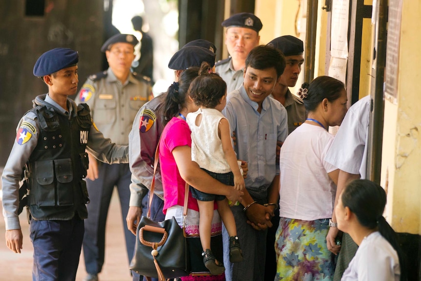 Reuters journalist Kyaw Soe Oo greets his wife Chit Su Win and daughter outside the court