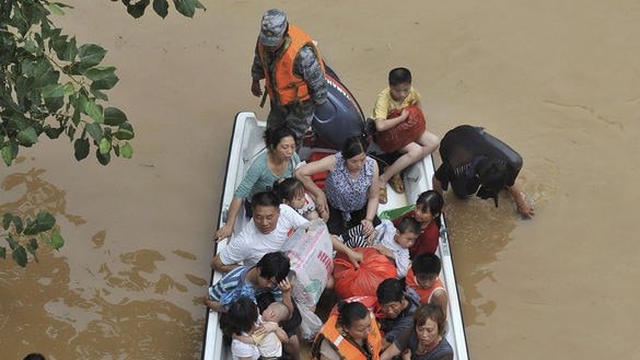 Chinese police use a boat to transfer locals to a safer area on a flooded street in Fuzhou, Jiangxi