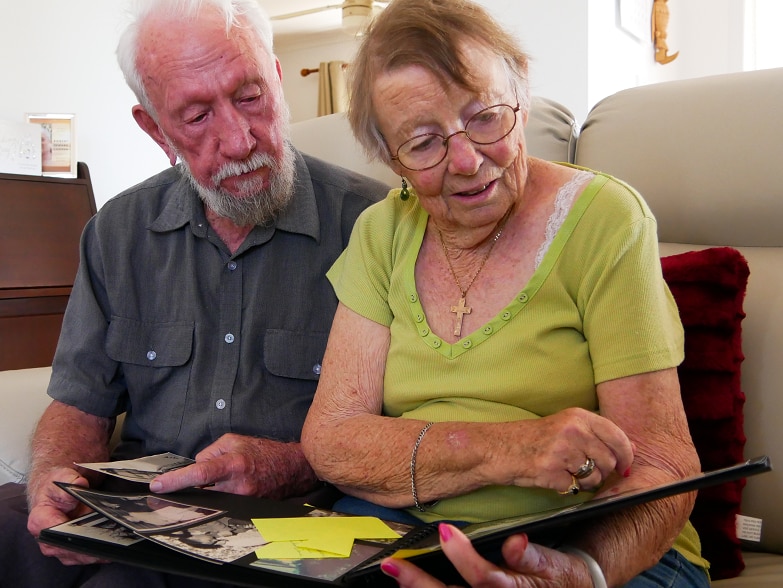 A mature-age couple sits and looks through photo album.