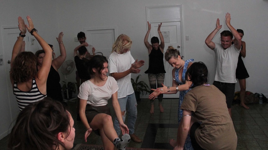 People dance freely around a large white room in Brisbane while letting go of their inhibitions