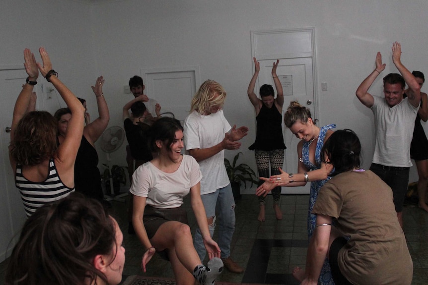 People dance freely around a large white room in Brisbane while letting go of their inhibitions