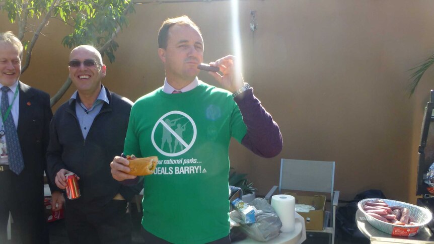 Jeremy Buckingham eating a sausage at a BBQ.