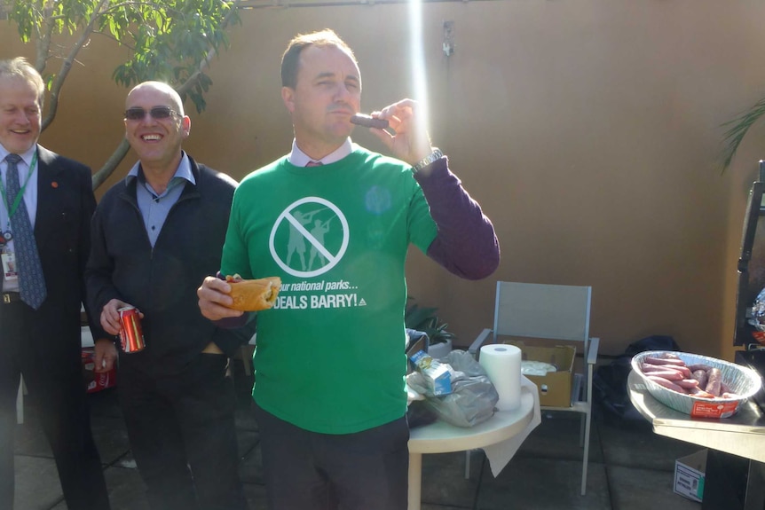 Jeremy Buckingham eating a sausage at a BBQ.