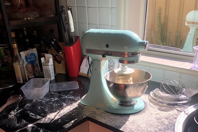 A mixer on a kitchen bench with flour spread everywhere