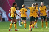 Matildas players, including Mary Fowler and Courtney Nevin, high five during a football game.