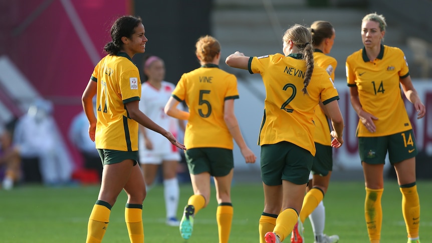 Matildas players, including Mary Fowler and Courtney Nevin, high five during a football game.
