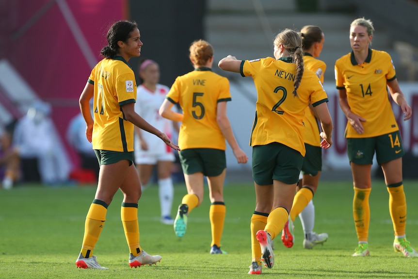 Matildas players, including Mary Fowler and Courtney Nevin, high five during a football game.