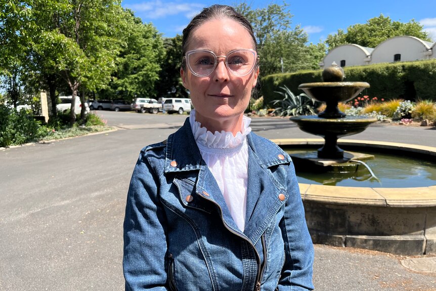 A woman wearing a denim jacket and glasses. 