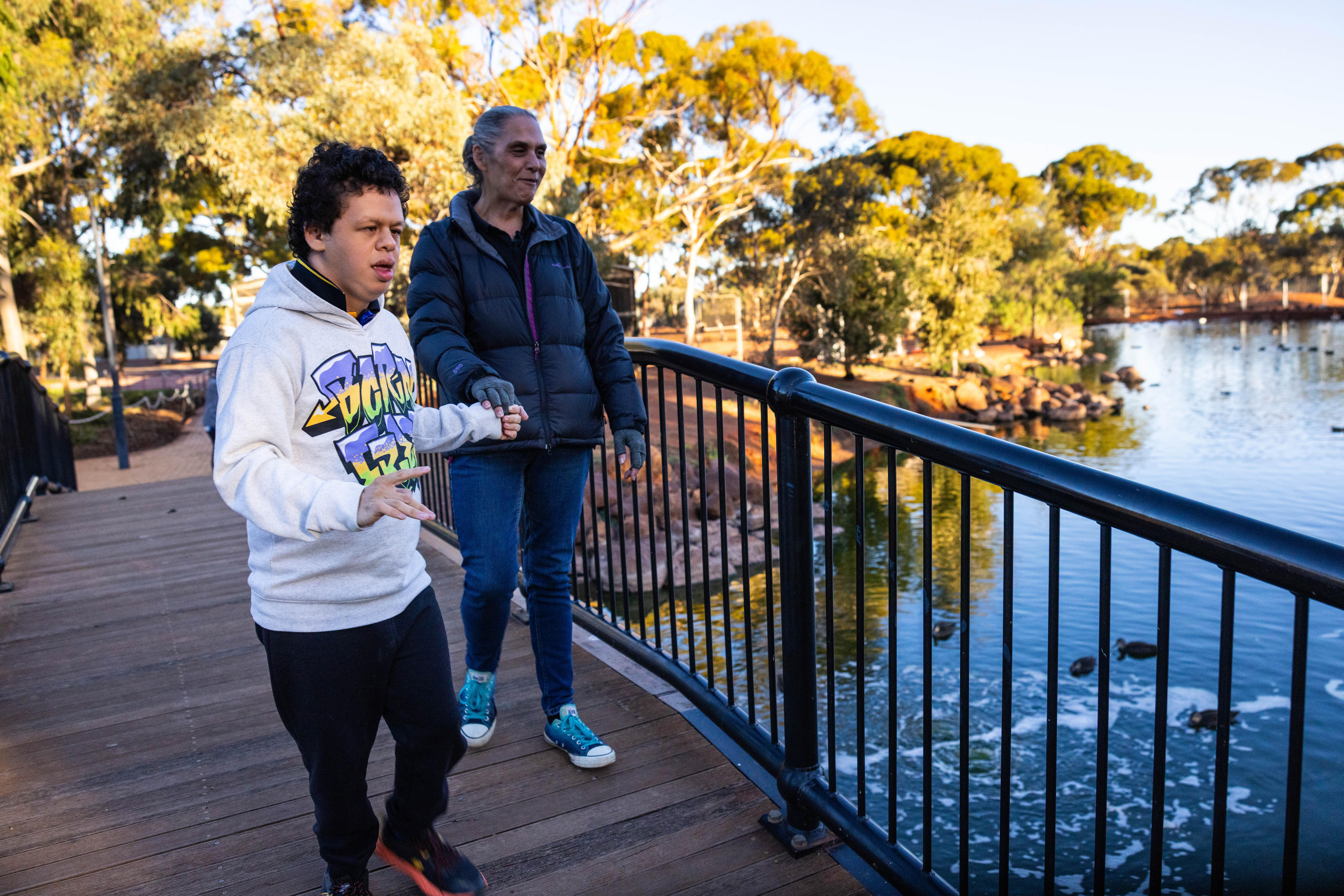 A mother and son walking in a park.  