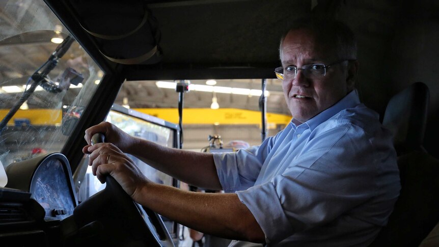 Scott Morrison looks at the camera while sitting in the front seat of a military truck