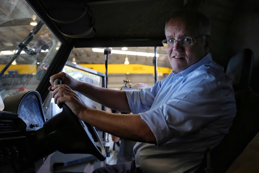 Scott Morrison looks at the camera while sitting in the front seat of a military truck