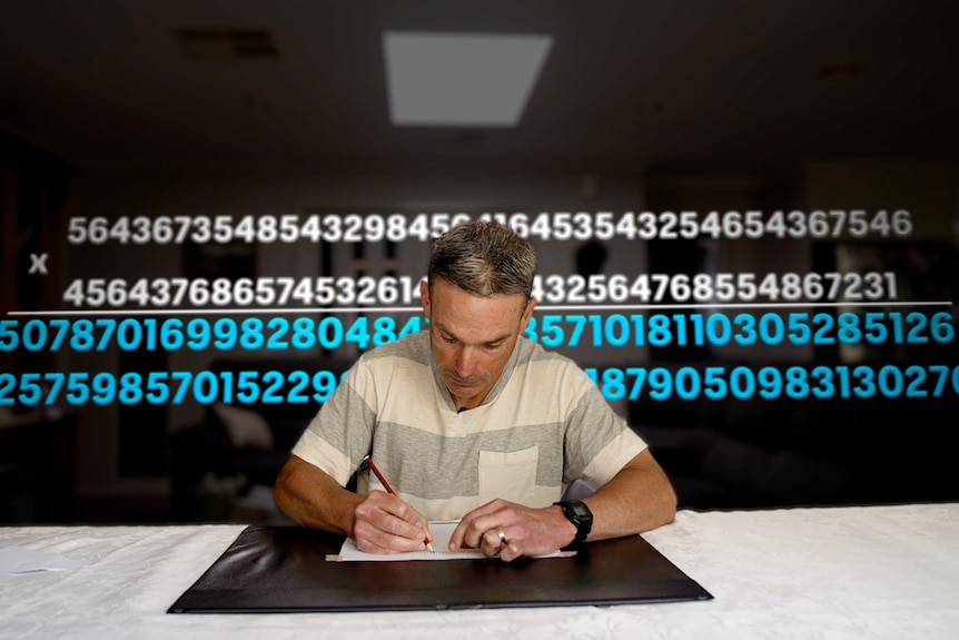 A man sits in front of a screen with lots of numbers