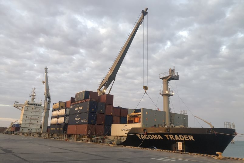 A large ship carrying seas containers docks. 