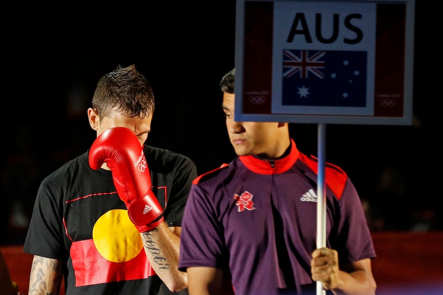 Damien Hooper walks to the ring wearing a T-shirt bearing the Aboriginal flag.