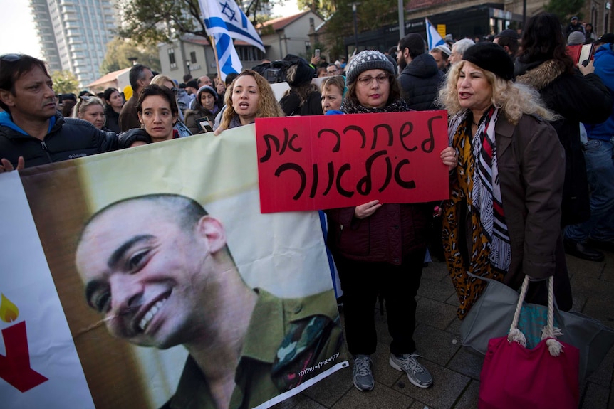Supporters of Israeli soldier Elor Azaria hold up a photo and signs.
