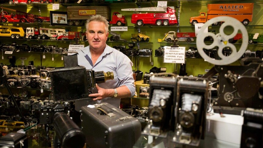 Owner of the antique shop John Cole surrounded by his camera collection