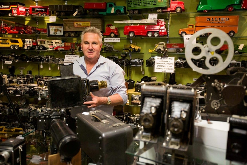 Owner of the antique shop John Cole surrounded by his camera collection