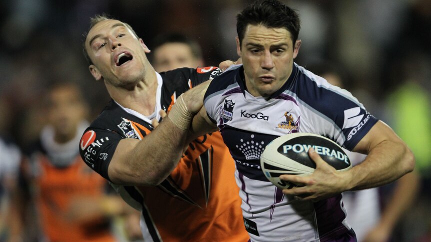 Cooper Cronk fends off the tackle of departing Tiger Gareth Ellis.