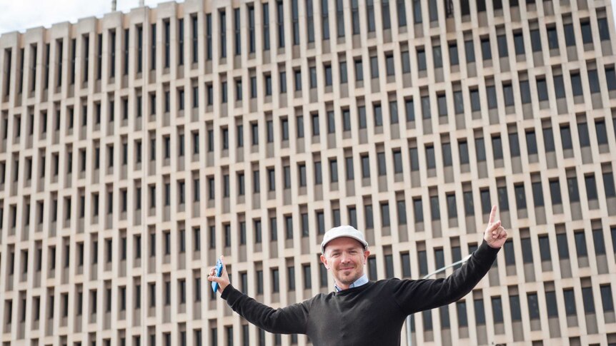 Adelaide inventor Ryan Osbourne stretches his arms out in front of the large ABC Collinswood building
