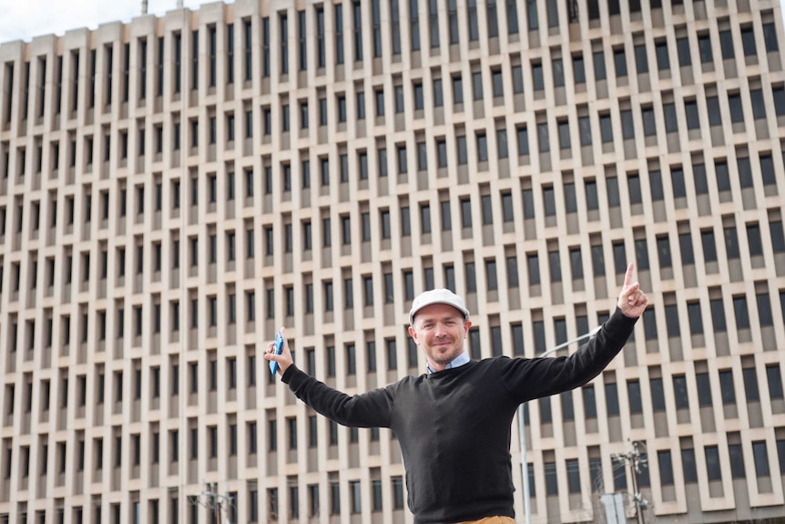 Adelaide inventor Ryan Osbourne stretches his arms out in front of the large ABC Collinswood building