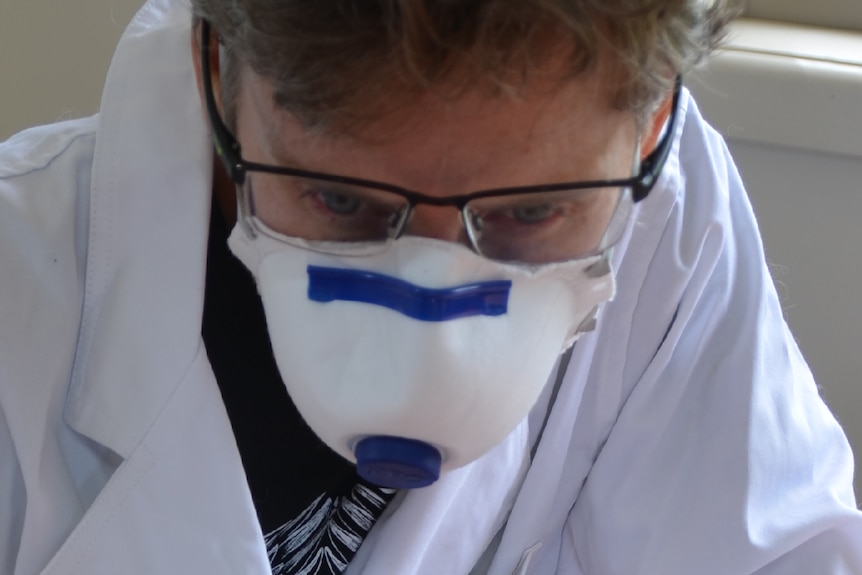 Adjunct researcher Dr Jackie Wright wears a lab coat and face mask as she swabs part of a table to traces of the drug.