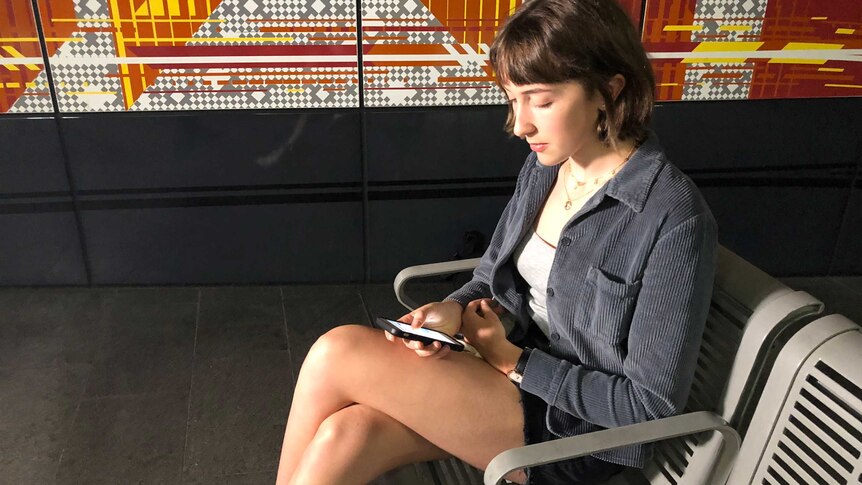 Lauren Lancaster uses her phone while waiting for public transport