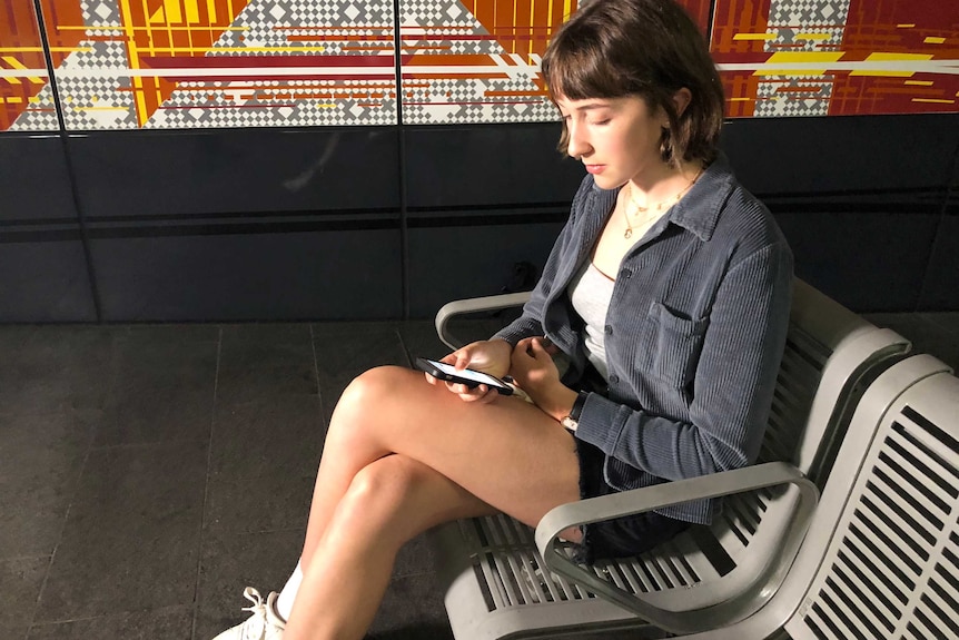 Lauren Lancaster uses her phone while waiting for public transport