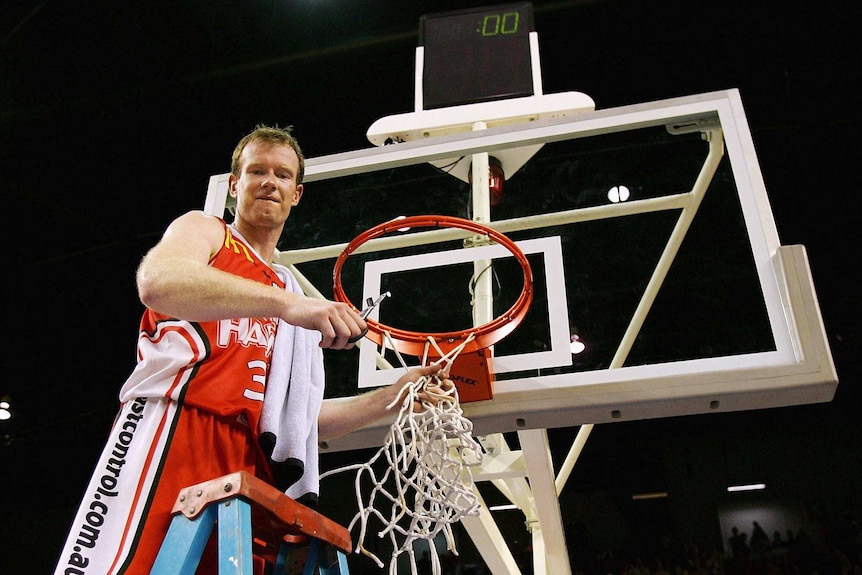 Mat Campbell cuts down the net while standing on a ladder during his playing days for the Hawks.