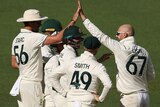 Nathan Lyon high-fives a teammate as the Australians converge in a huddle