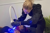 A woman whitens a client's teeth