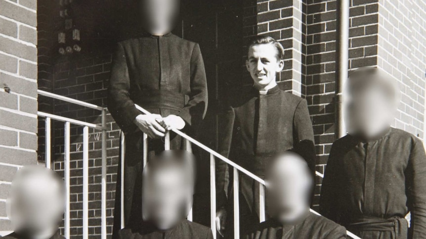 A group of men wearing the black habit of the Christian Brothers pose for a photo.