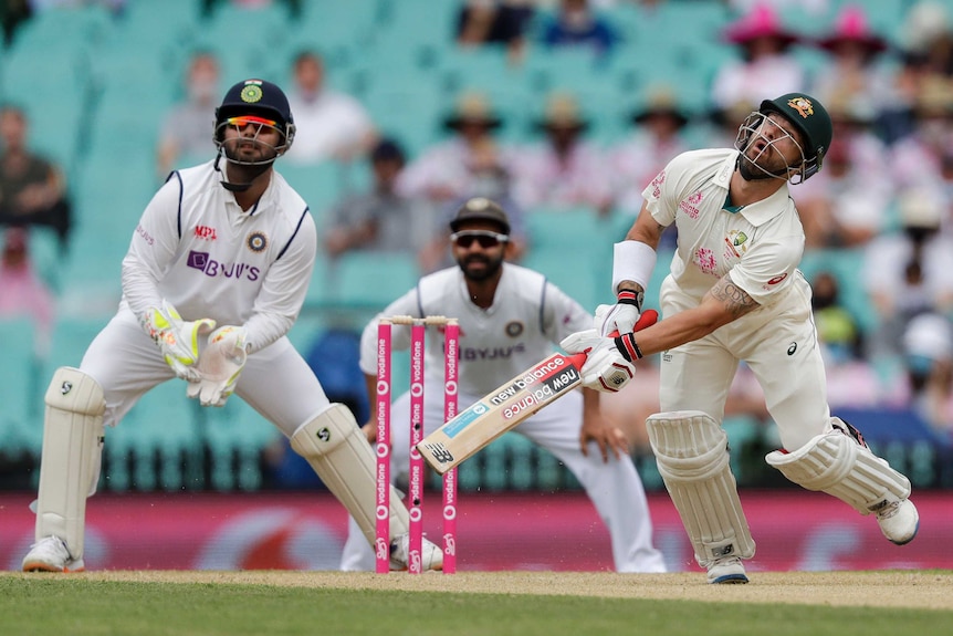 Matthew Wade, holding a bat and stumbling, looks up in the air next to Rishabh Pant.