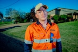 A man in hi-vis on a street in suburbia
