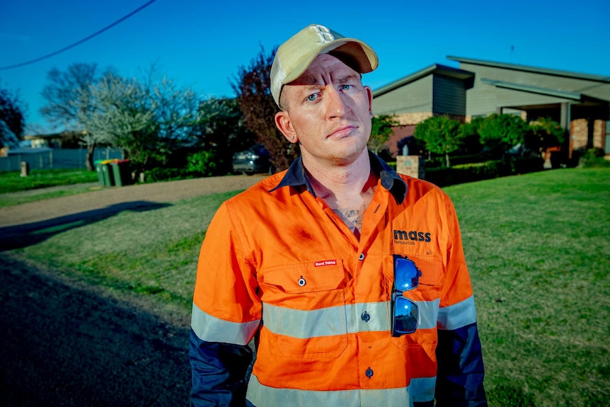 A man in hi-vis on a street in suburbia